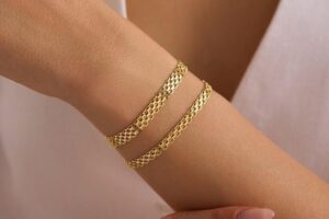 Två guldfärgade Bismarckarmband runt en handled