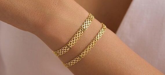 Två guldfärgade Bismarckarmband runt en handled