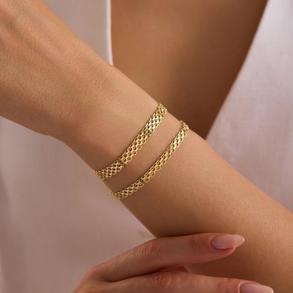 Två guldfärgade Bismarckarmband runt en handled