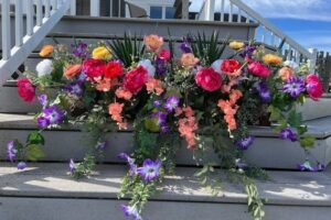 Färgstark blomlåda med rosor och lila blommor på en trappa