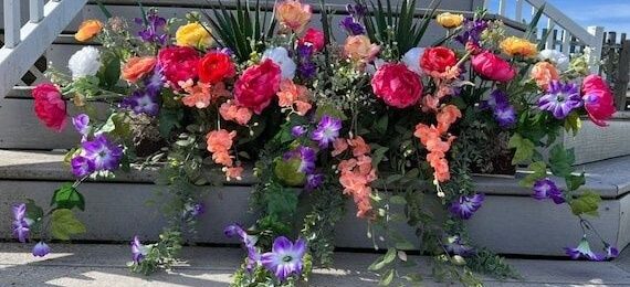 Färgstark blomlåda med rosor och lila blommor på en trappa